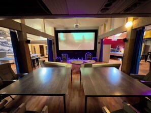 A conference room with a large screen, wooden tables, and a neon sign. -   Premium Stay Academy - Luxus-Ferienwohnungen mit Erlebnis (Bad Ems)