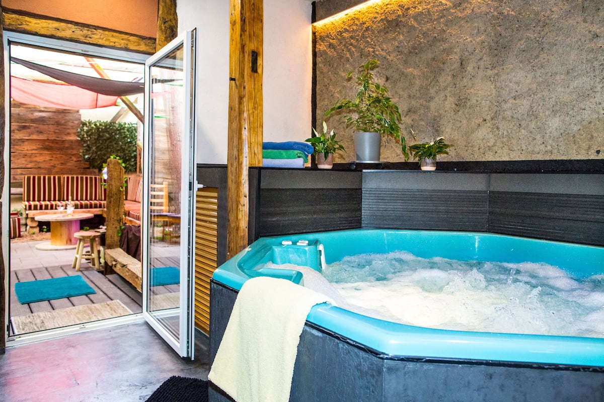 Un espace bien-être comprenant un jacuzzi, des bancs en bois et des plantes en pot.