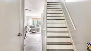 A modern staircase with a white wall and dark steps leading to a living area with a sofa and coffee table.