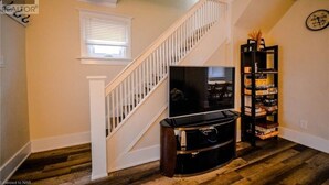 Una sala de estar con una escalera, un televisor de pantalla plana y una estantería.