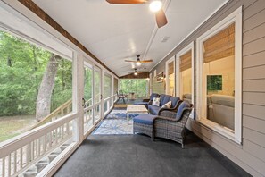 A covered porch with a sofa, a table, and a ceiling fan.