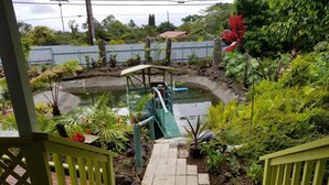 Ein Garten mit einem kleinen Teich, einer Holzbrücke und vielfältigen Pflanzen.