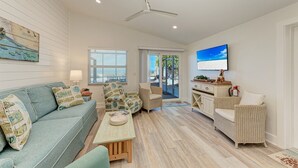 A spacious living room with a sofa, chairs, a coffee table, and a television. - Fins to the Right: On the Gulf of Mexico! Beach! (Holmes Beach)