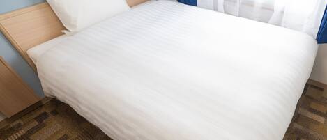 A neatly made bed with white bedding, a wooden headboard, and a patterned carpet.