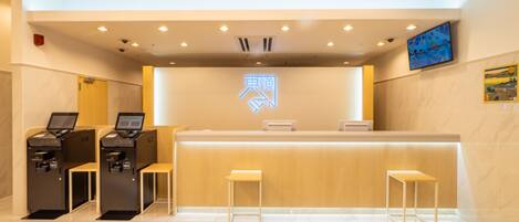 A reception area with a counter, two computer stations, and a neon sign.