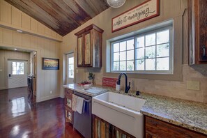 A kitchen with a large window, wooden cabinets, and a granite countertop. - Wooded lot with pond, deer feeder, 3 minutes to downtown Brenham. (Brenham)