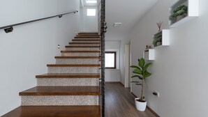 A staircase with wooden steps and a metal handrail, leading to a room with a window and a potted plant. - Villa Stonehouse (Istria - Umag) (Umag)