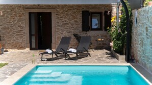 A stone building with a swimming pool, two lounge chairs, and a small table with a bottle and glasses. - Villa Stonehouse (Istria - Umag) (Umag)