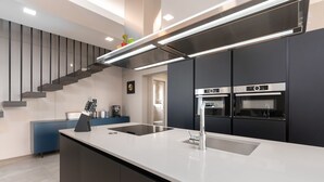 A modern kitchen with a central island, built-in ovens, and a sleek staircase. - Villa Panamera (Istria - Poreč) (Poreč)