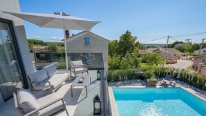 A modern outdoor balcony with a glass enclosure, a pool, and a seating area with a table and chairs. - Villa Panamera (Istria - Poreč) (Poreč)