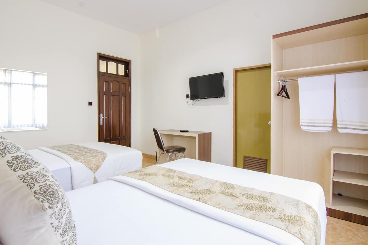 A hotel room with two beds, a desk, a TV, and a wardrobe.