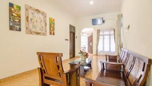 A hotel lobby with wooden furniture, a flat-screen TV, and artwork on the walls. - Shakila Guest House (Batu)