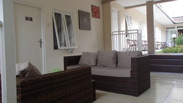 A living room with a sofa and two wicker chairs, a door labeled '101', and a window with blinds. - Shakila Guest House (Batu)