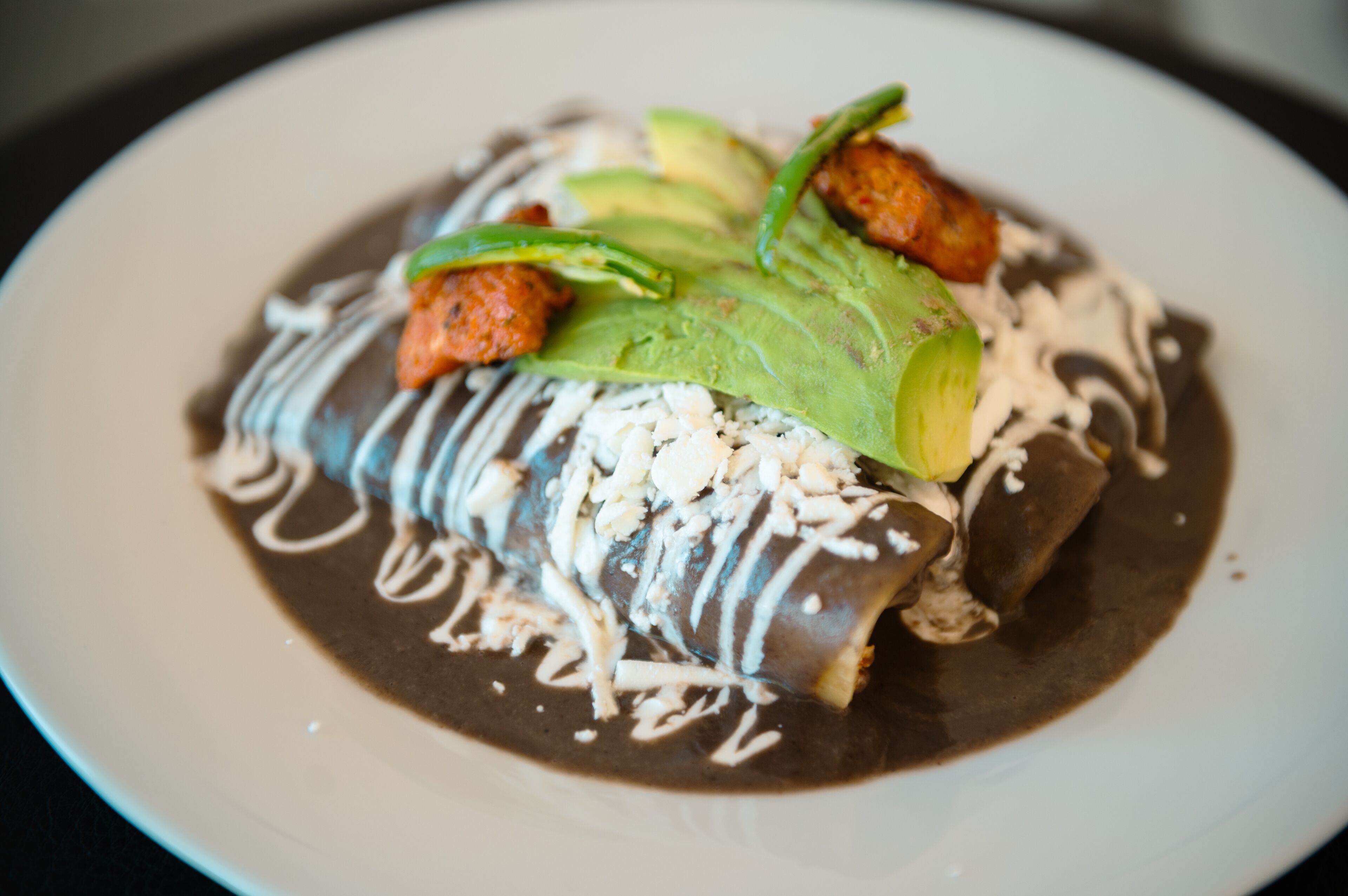 Un dessert composé d’une sauce au chocolat, d’avocat et d’une garniture crémeuse blanche, le tout présenté dans une assiette.