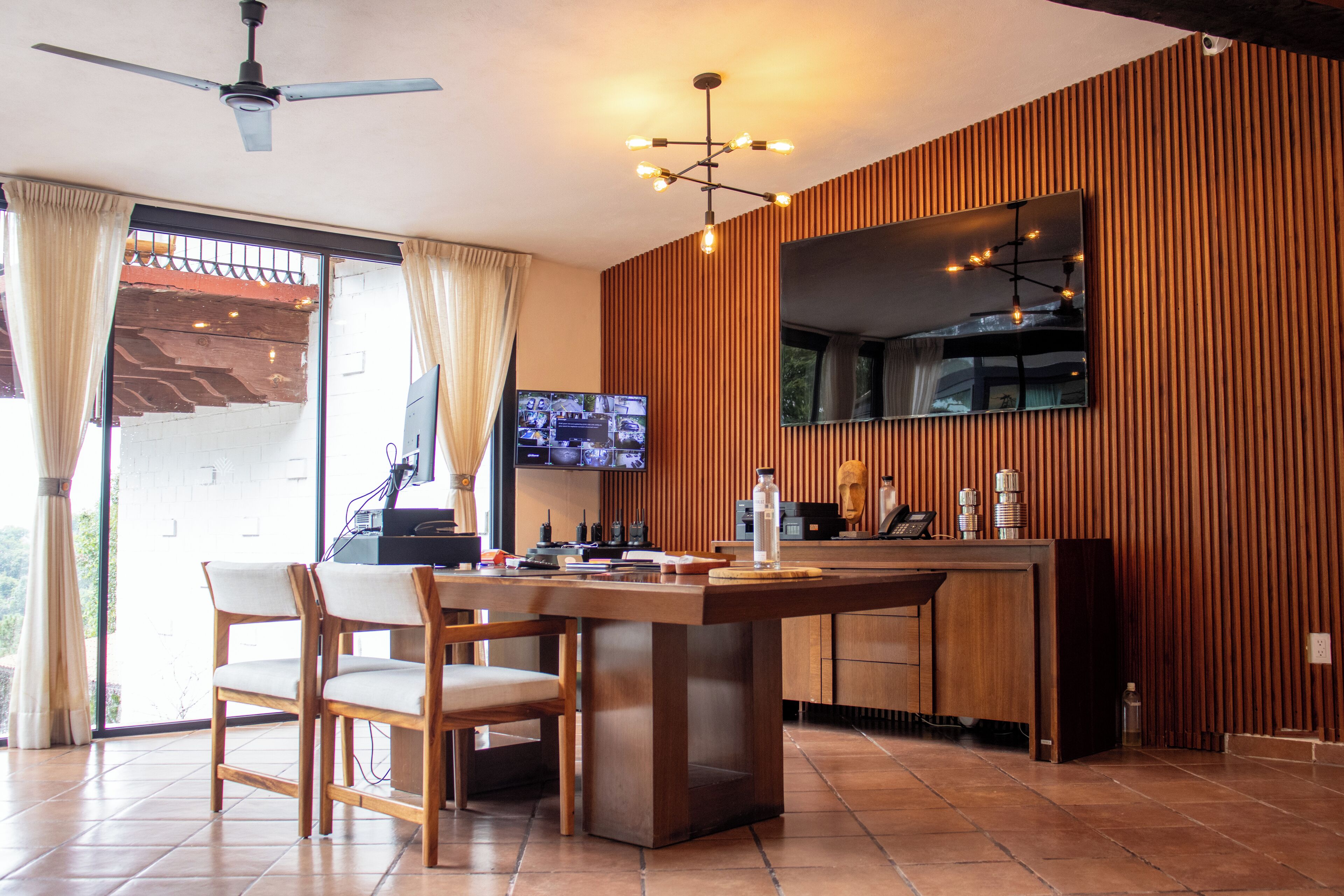 Una cocina moderna con una isla de madera, un televisor montado en la pared y un ventilador de techo.