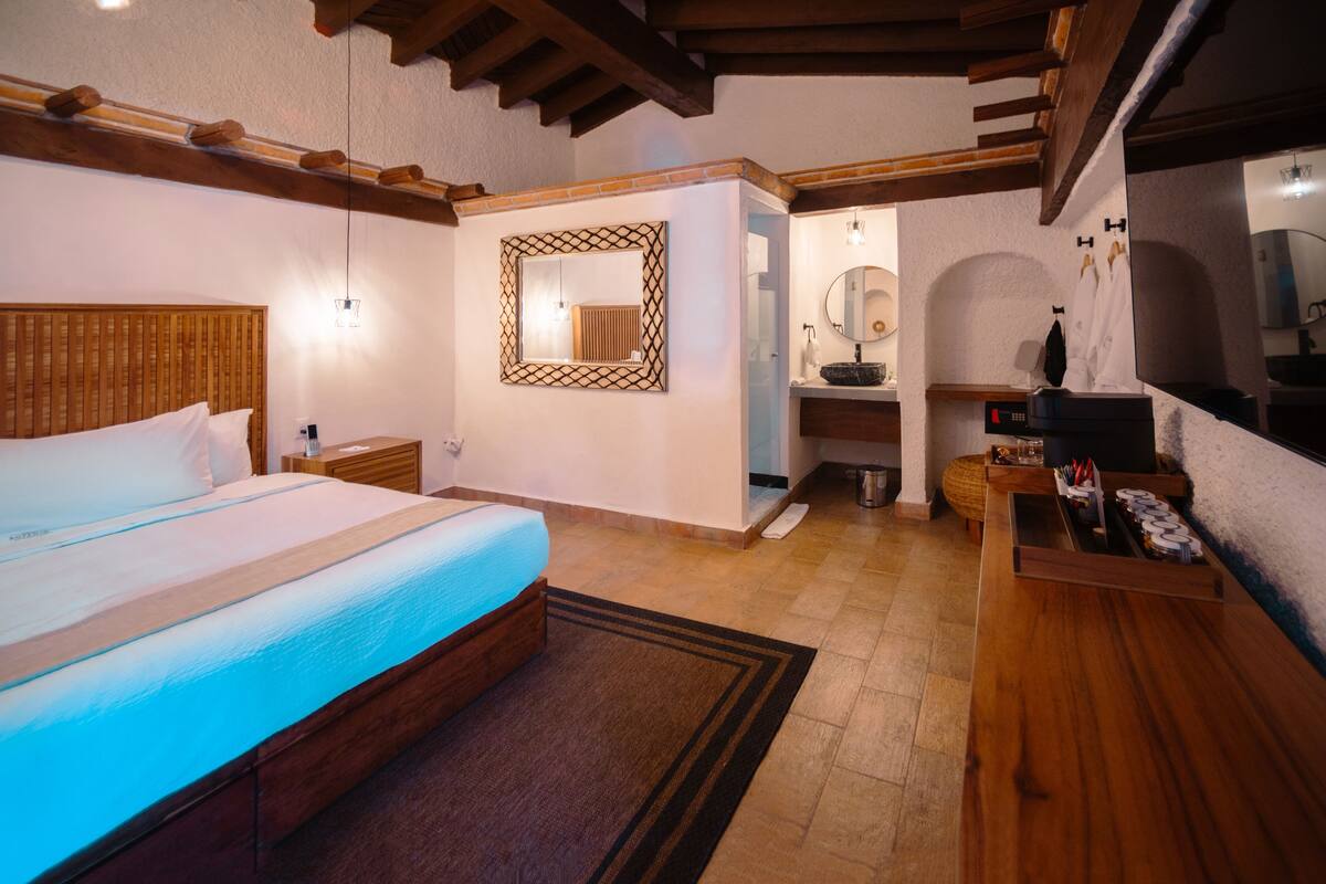 A bedroom with a wooden bed, a nightstand, a mirror, a vanity with a sink, and a wooden dresser.