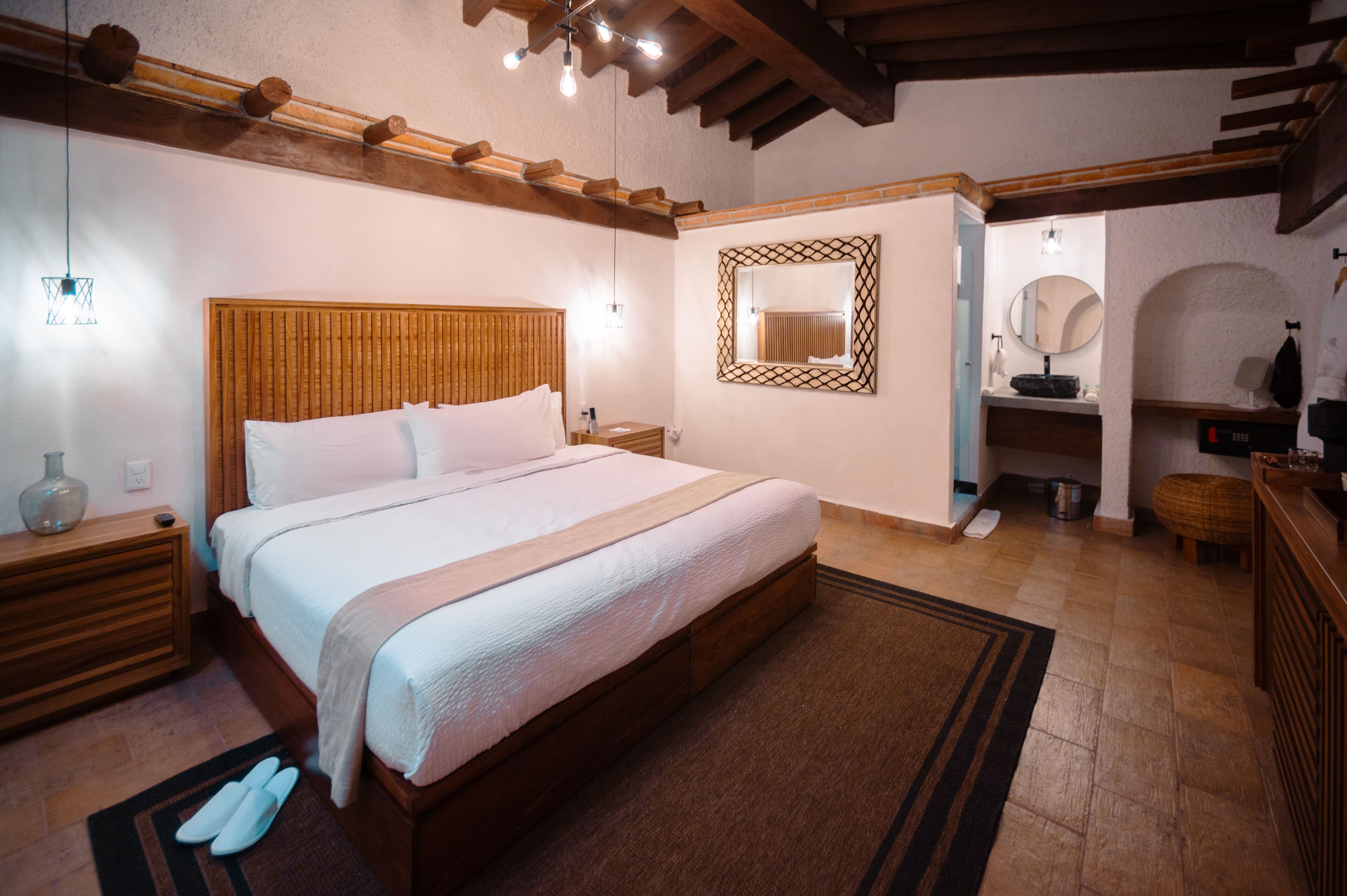 A bedroom with a wooden bed, bedside tables, a nightstand, a mirror, and a built-in bench.