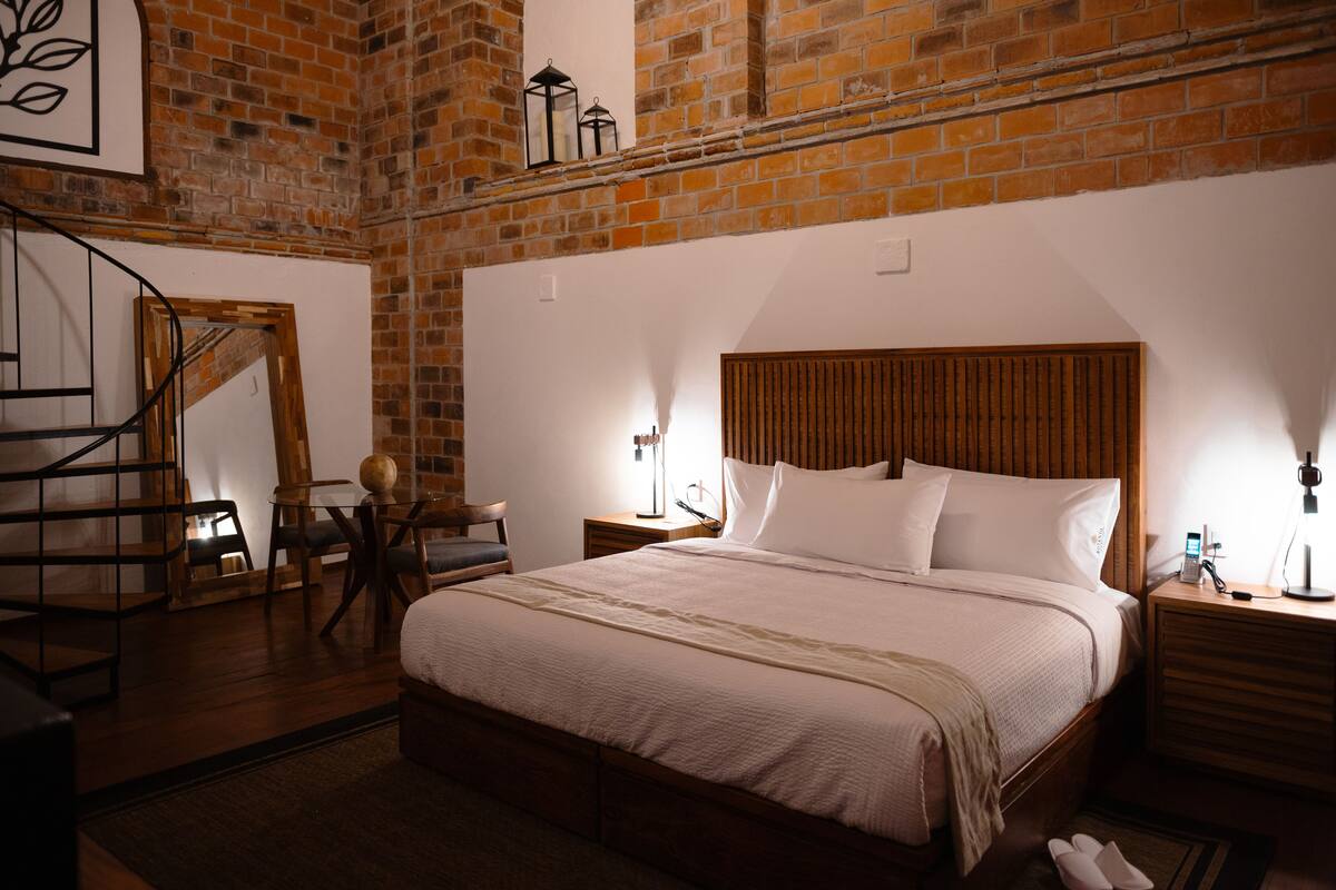 A bedroom with a wooden headboard, a large bed, a nightstand, a lamp, and a chair.