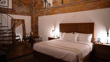 Un dormitorio con cabecera de madera, una cama grande, una mesita de noche, una lámpara y una silla.