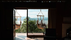 Habitación con un amplio ventanal corredero que da a un balcón con dos columpios y vistas a montañas.