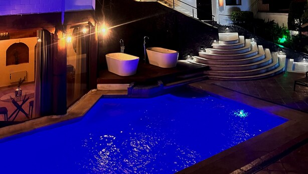 Una casa moderna con piscina, una escalera que lleva a un balcón e interior bien iluminado.