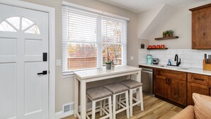 A kitchen with a white countertop, wooden cabinets, a sink, and a window with blinds. - Welcome to the Boar's Nest, walking distance to Noblesville town square  (Noblesville)