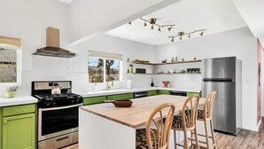 A modern kitchen with a central island, green cabinets, a stainless steel range, and a built-in oven. - Stargazer Ranch - Stunning 5 BR + Hot Tub, Pool, Fire Pit (Yucca Valley)