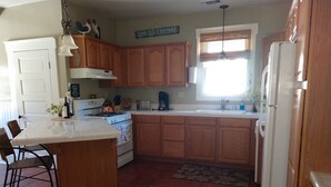 A kitchen with wooden cabinets, a white refrigerator, a stove, and a sink. - Cozy Home on Vine Street  (Paso Robles)