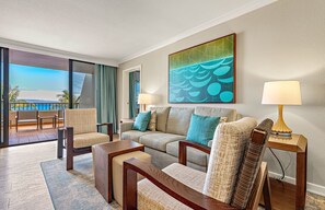 Une chambre d’hôtel avec un canapé, des fauteuils, une table basse, une lampe et un tableau.