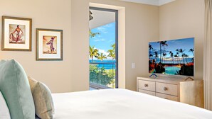 A hotel room with a bed, a dresser, and a TV displaying a tropical beach scene.
