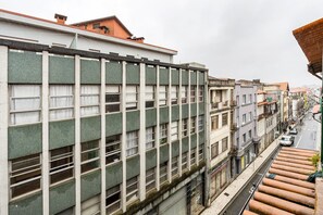A multi-story building with a grid of windows and balconies, adjacent to a street with parked cars and a tram line.