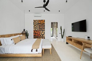 A modern bedroom with a large bed, a ceiling fan, a TV, and a desk. - Marbella Villa by DH (Ubud)