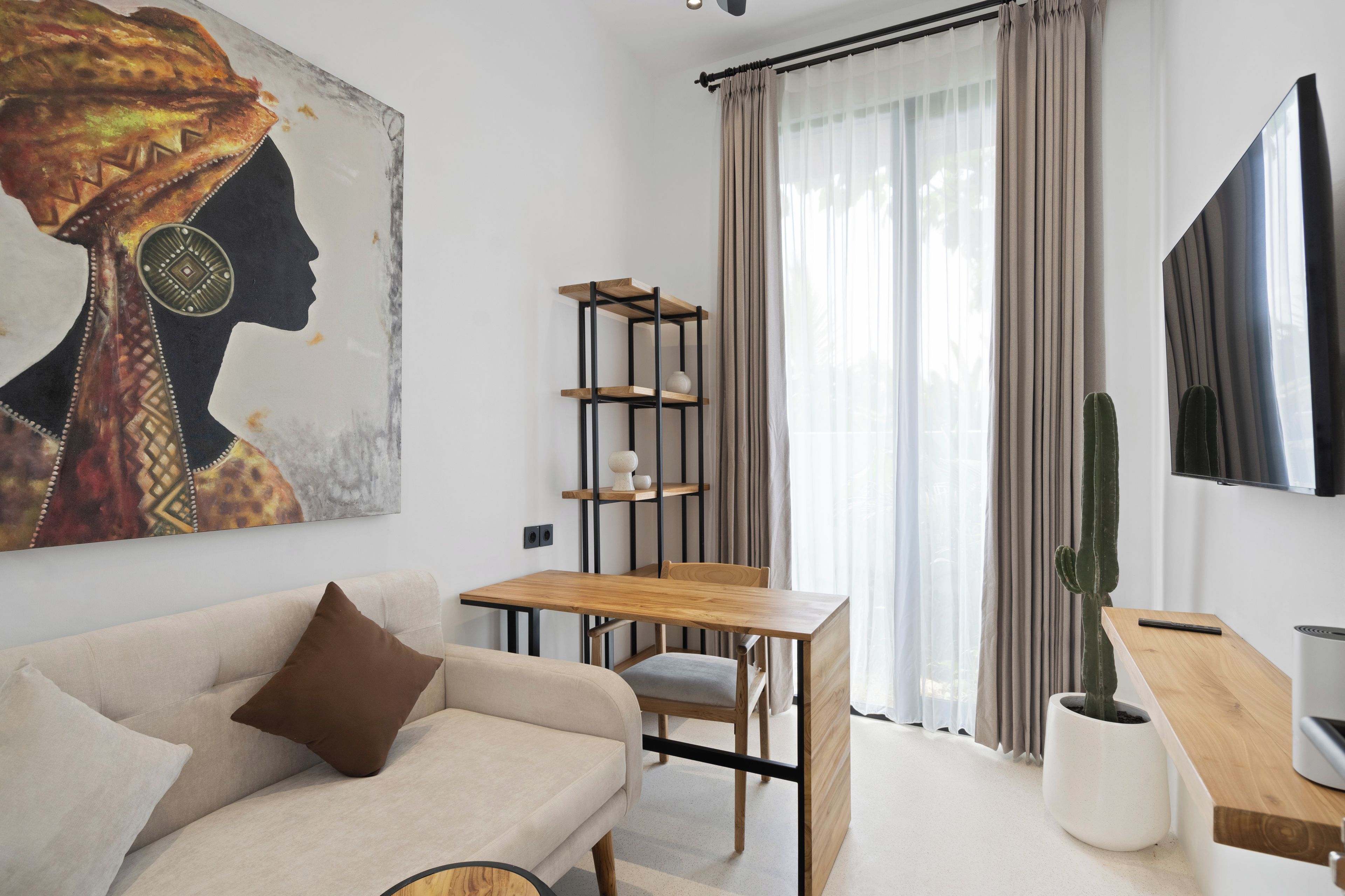 A modern living room with a sofa, a wooden coffee table, a TV mounted on the wall, a bookshelf, and a large painting.