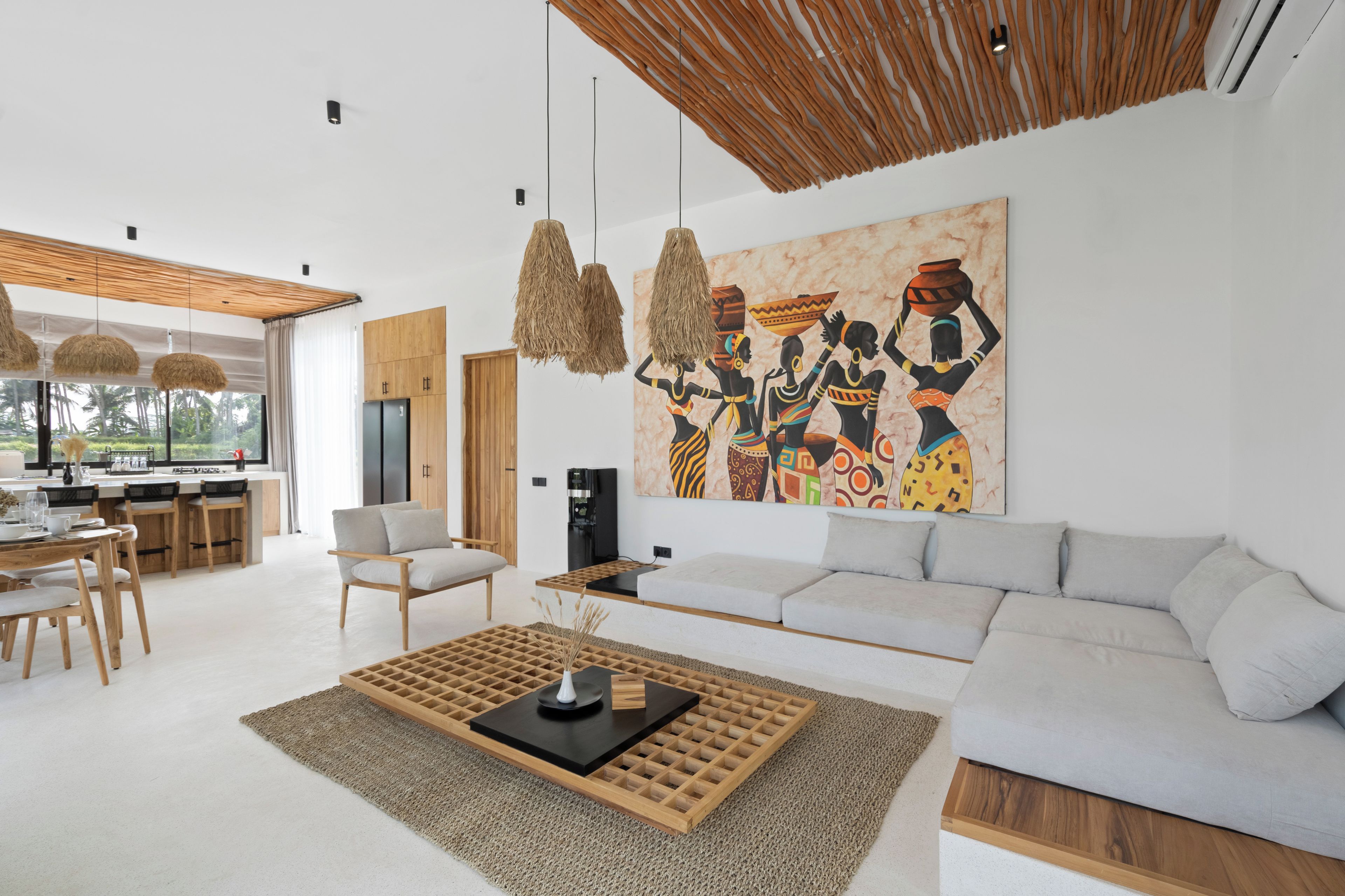 A modern living room with a large sofa, a coffee table, and a dining area with chairs and a table.