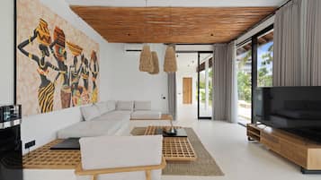 A modern living room with a sectional sofa, a flat-screen TV, and a large abstract painting on the wall.