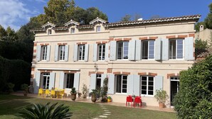 Un bâtiment à deux étages doté d’un patio avec jardin, d’un espace extérieur aménagé pour s’asseoir et de plantes en pot.