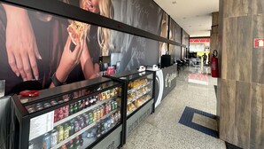 Un espace restauration avec une publicité pour une pizzeria, un réfrigérateur pour boissons et un extincteur.