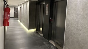 Un couloir avec un extincteur, une porte portant un panneau «interdiction de fumer» et un ascenseur.