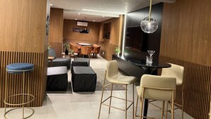 Un espace repas moderne avec une table ronde, des tabourets de bar et un plafond haut doté d’un éclairage encastré.