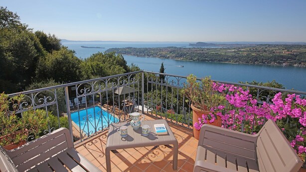 Una terraza con piscina, muebles de exterior y vistas a un lago.