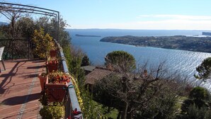 Una terraza con plantas en macetas, con vistas a un paisaje costero y al mar, con islas en la distancia.