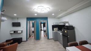 Une chambre d’hôtel équipée d’une kitchenette, d’un téléviseur fixé au mur, d’un bureau et d’une chaise.