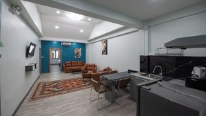 Une cuisine moderne avec un coin repas, un salon agrémenté d’un mur d’accent bleu et un grand tapis.