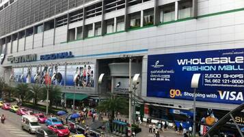 A busy street with a large building labeled "Platinum Fashion Mall" featuring a blue sign advertising wholesale shops and VISA card acceptance.