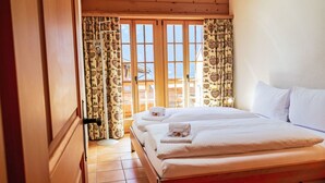 A bedroom with a wooden bed, two white pillows, and a neatly made bed with a towel.