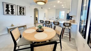 A modern dining area with a round table, chairs, and a hanging light fixture. - Picturesque Punta Gorda Condo on Golf Course with Nature Preserve Views! (Punta Gorda)