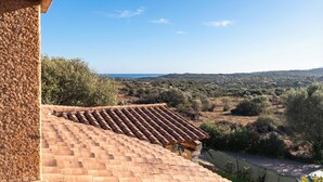 A terracotta-tiled roof, a stone wall, and a view of a hilly landscape with sparse vegetation. - Quiet Sanibel, Monte Petrosu, Italy (Monte Petrosu)