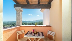 A balcony with a table and chairs, a view of the countryside, and a wooden ceiling. - Quiet Sanibel, Monte Petrosu, Italy (Monte Petrosu)