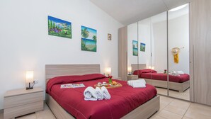 Habitación de hotel con una cama grande, una mesita de noche, un espejo y dos cuadros colgados en la pared.