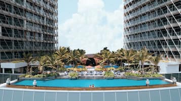A modern hotel with a central swimming pool surrounded by palm trees and lounge chairs.
